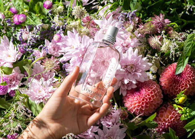 holding cherry blossom eau de toilette in front of garden and flowers